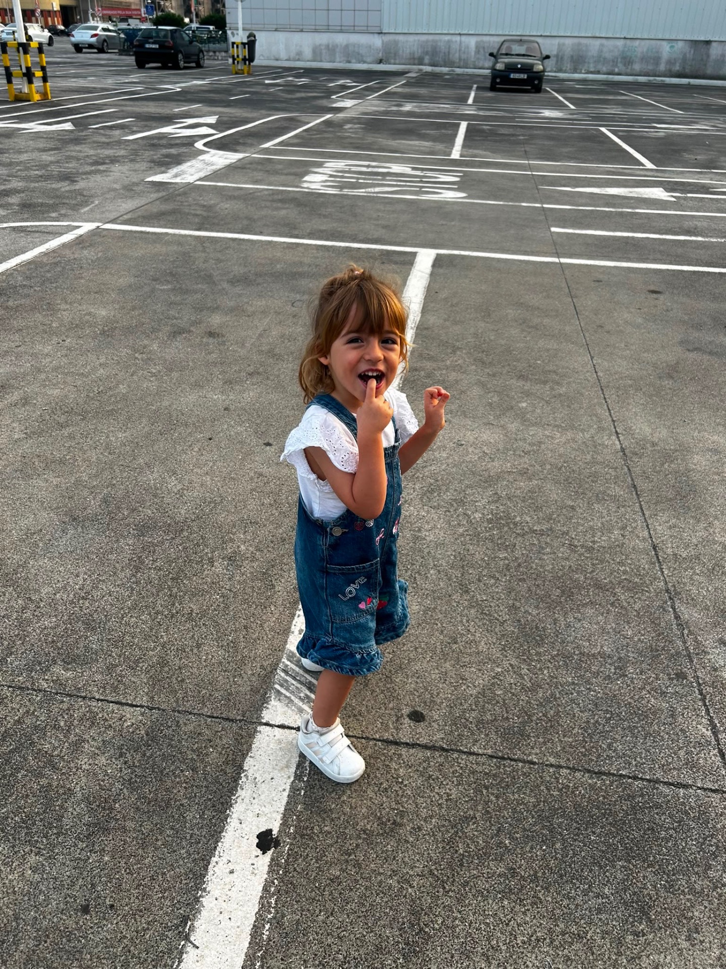 Matilde, uma menina de 3 anos, num parque de estacionamento ao ar livre